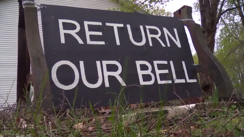 Hand-painted sign that reads: "Return Our Bell"