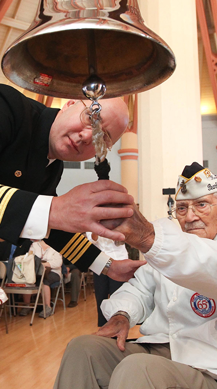 Naval officer helps a Veteran ring a bell