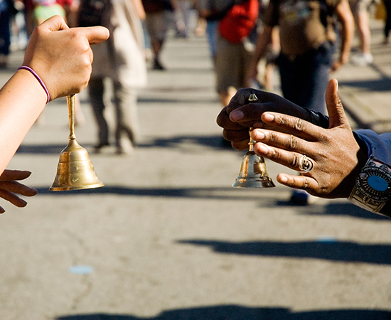 Two handheld bells are rung during a parade.