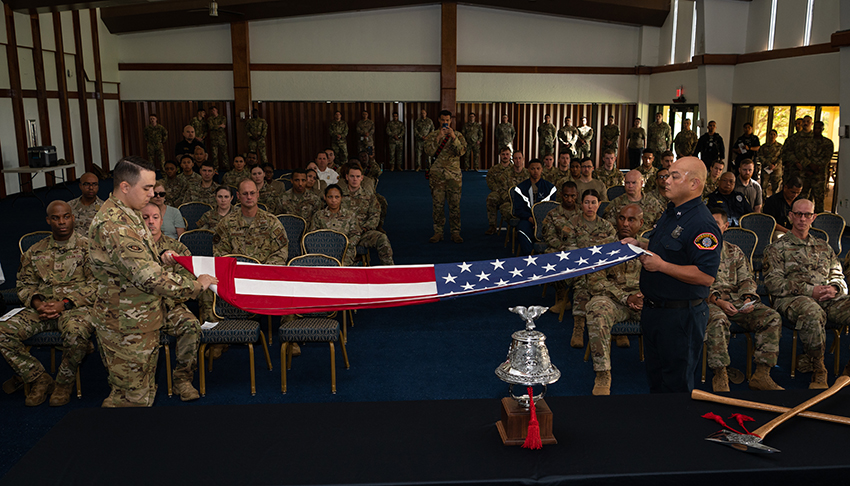 Andersen Air Force Base Fire Department firefighters fold the American flag and ring a bell during the 2023 9/11 Memorial Ceremony