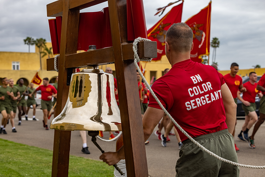 A U.S. Marine Corps Color Sergeant rings the First Battalion bell during a motivational run