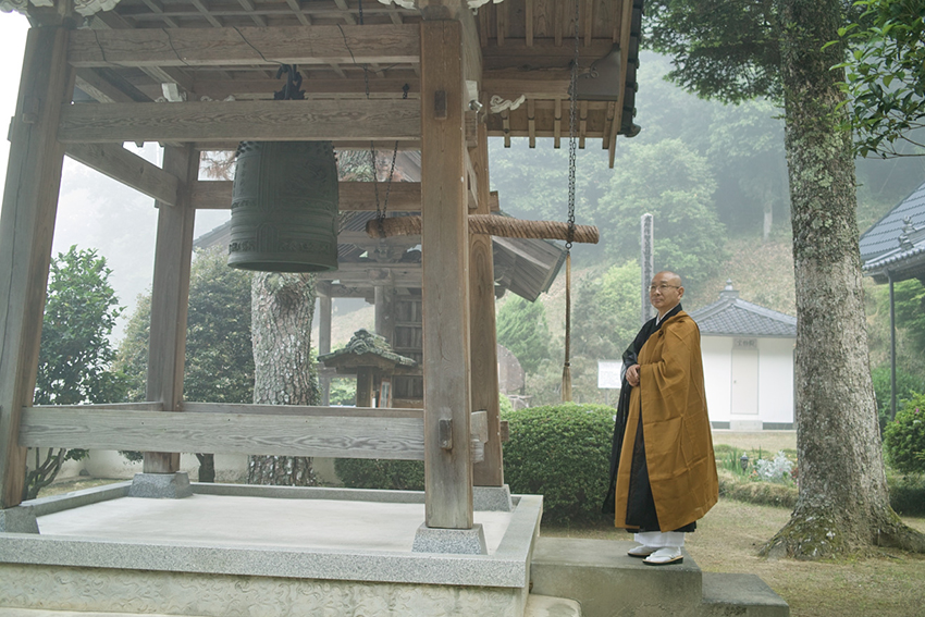 A monk stands before the replica Peace Bell in Japan