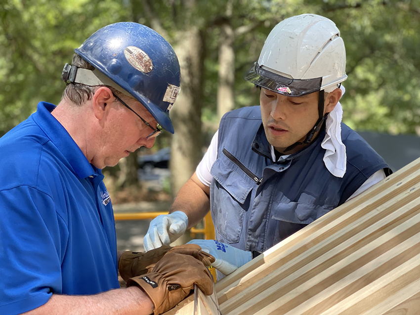 Carpenters Jim Whitcomb (left) and Daisuke Koyama work on the roof structure of the Peace Bell Tower.