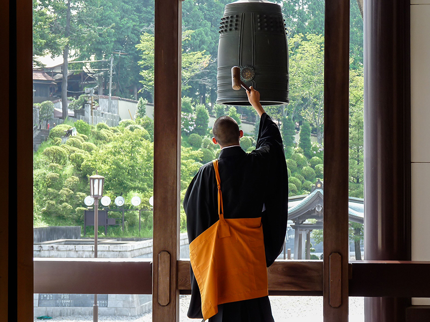 Monk rings a hanshō bell at a monastery in Japan
