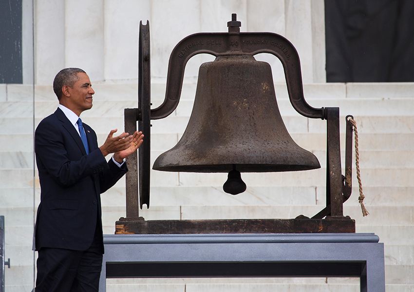 President Barack Obama claps next to a bell at the Lincoln Memorial