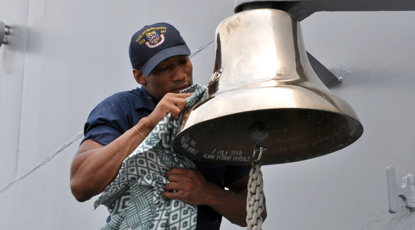 Sailor polishes a brass ship's bell