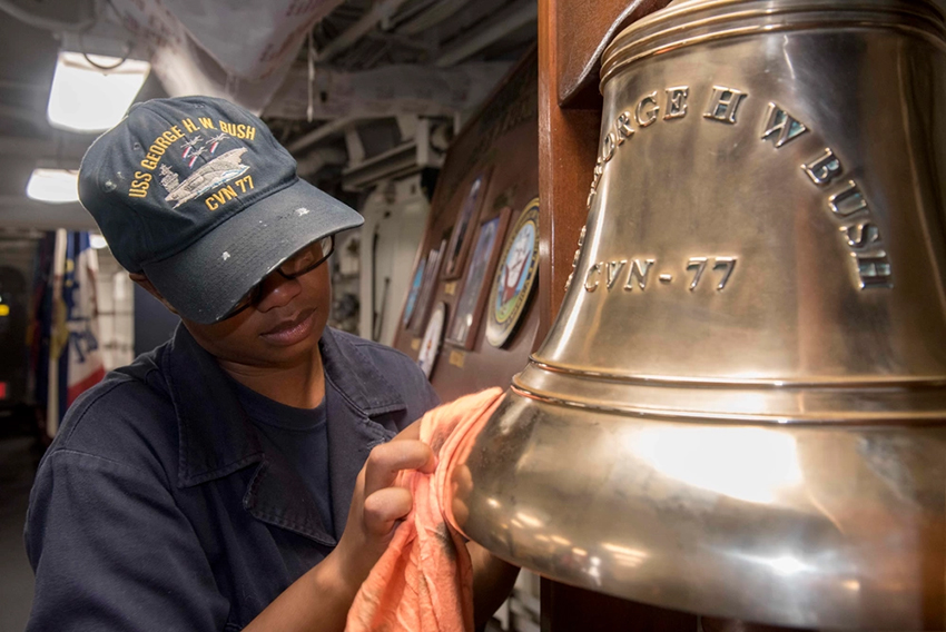 U.S. Navy sailor polishes the ship's bell aboard the USS George H. W. Bush