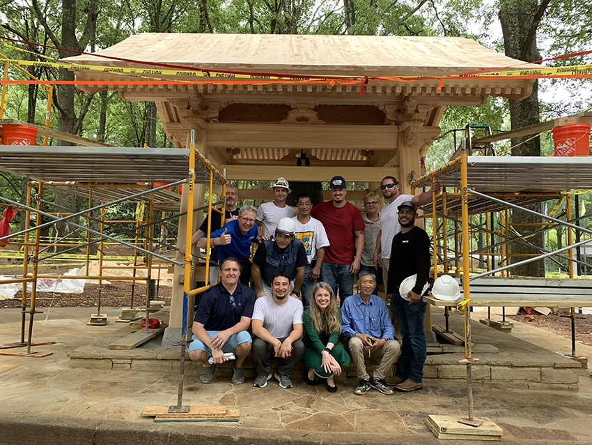 Teams from America and Japan Pose Alongside the Peace Bell Tower Under Construction