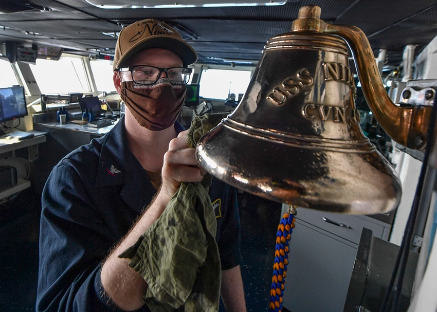 U.S. Navy sailor polishes a brass ship's bell