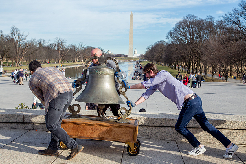 Volunteers roll a large bell onto the steps of the Lincoln Memorial